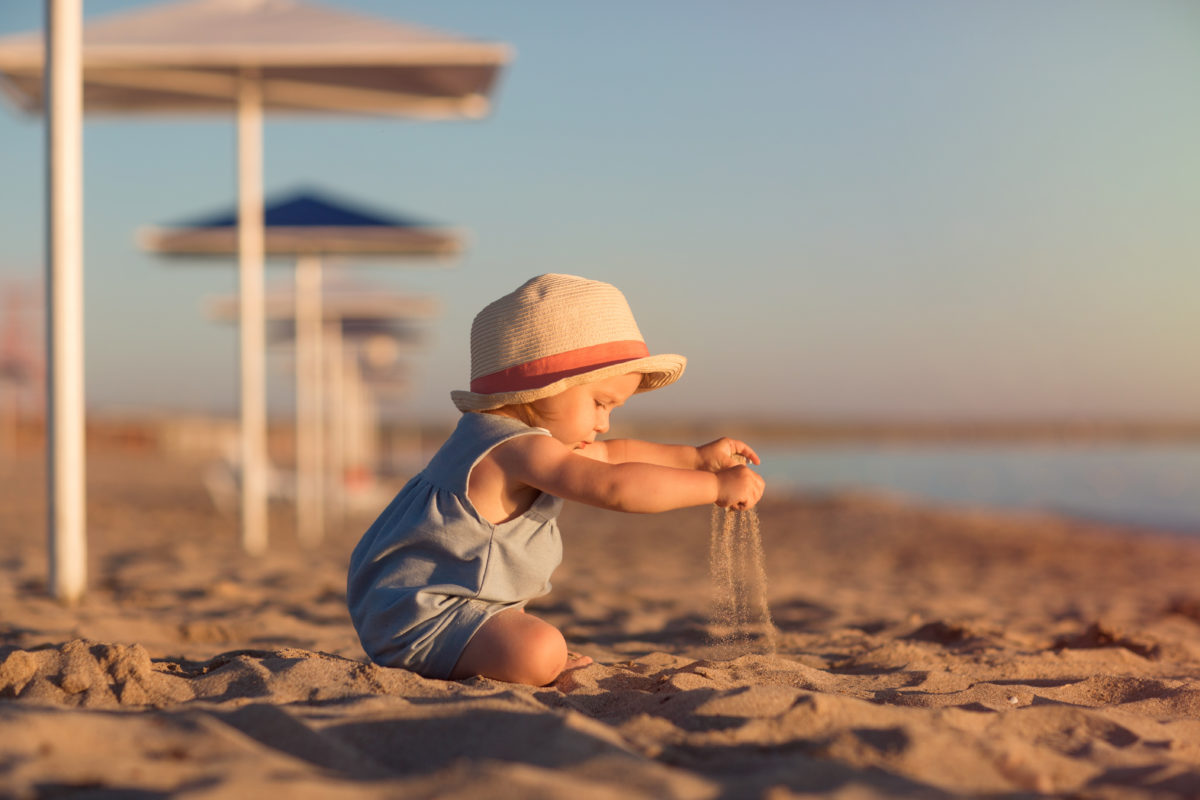 kind zit in het zand bij de zee
